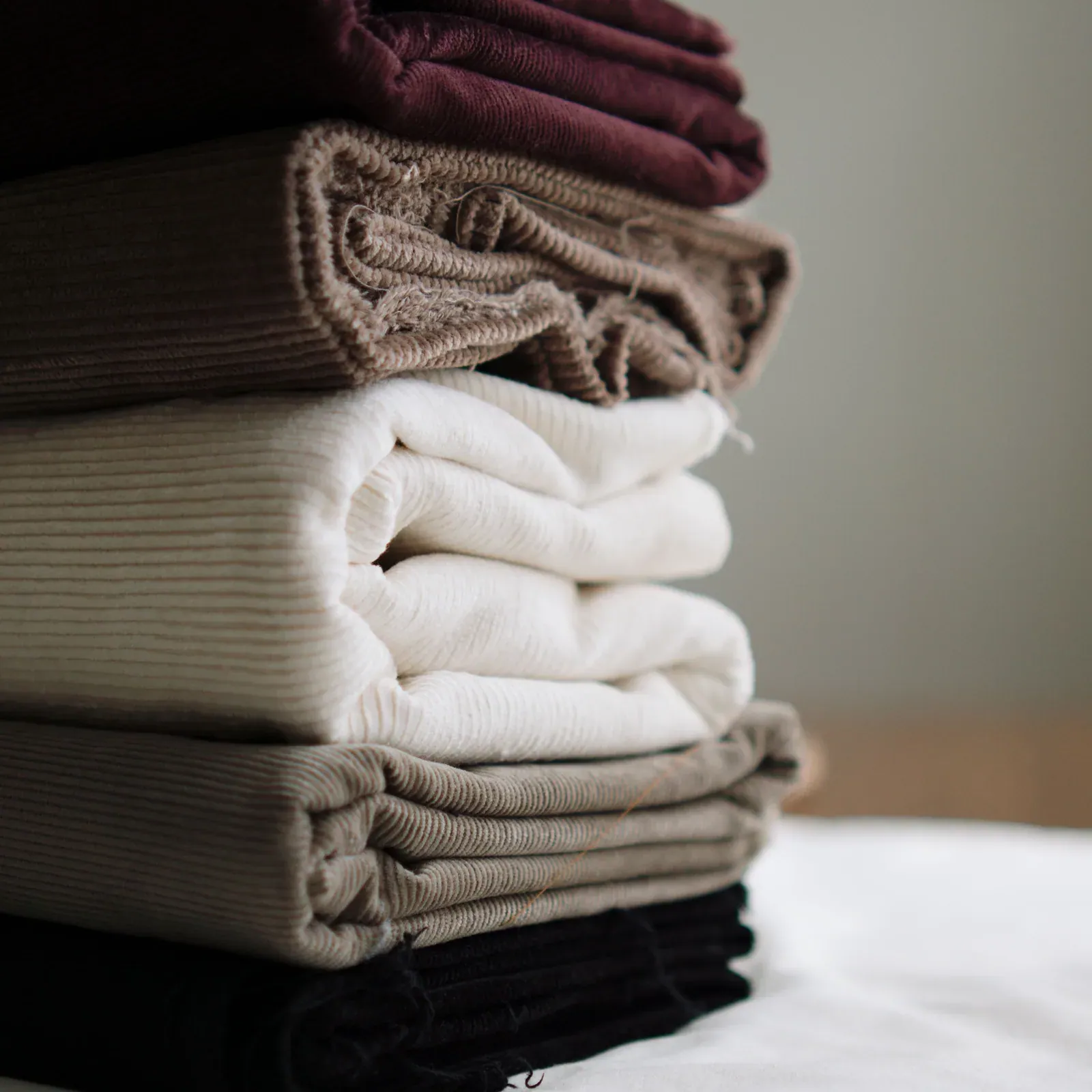 Stack of folded fabrics in burgundy, taupe, cream and black