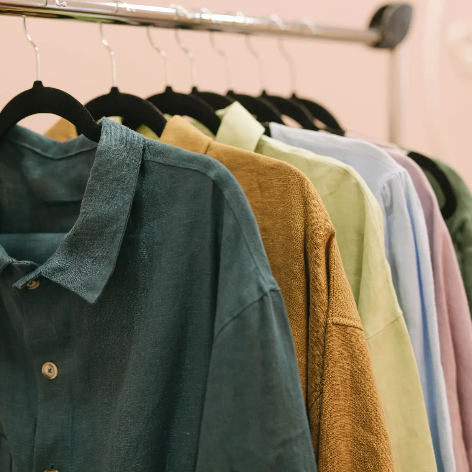 Long-sleeved shirts in green, mustard, sage and blush on black hangers