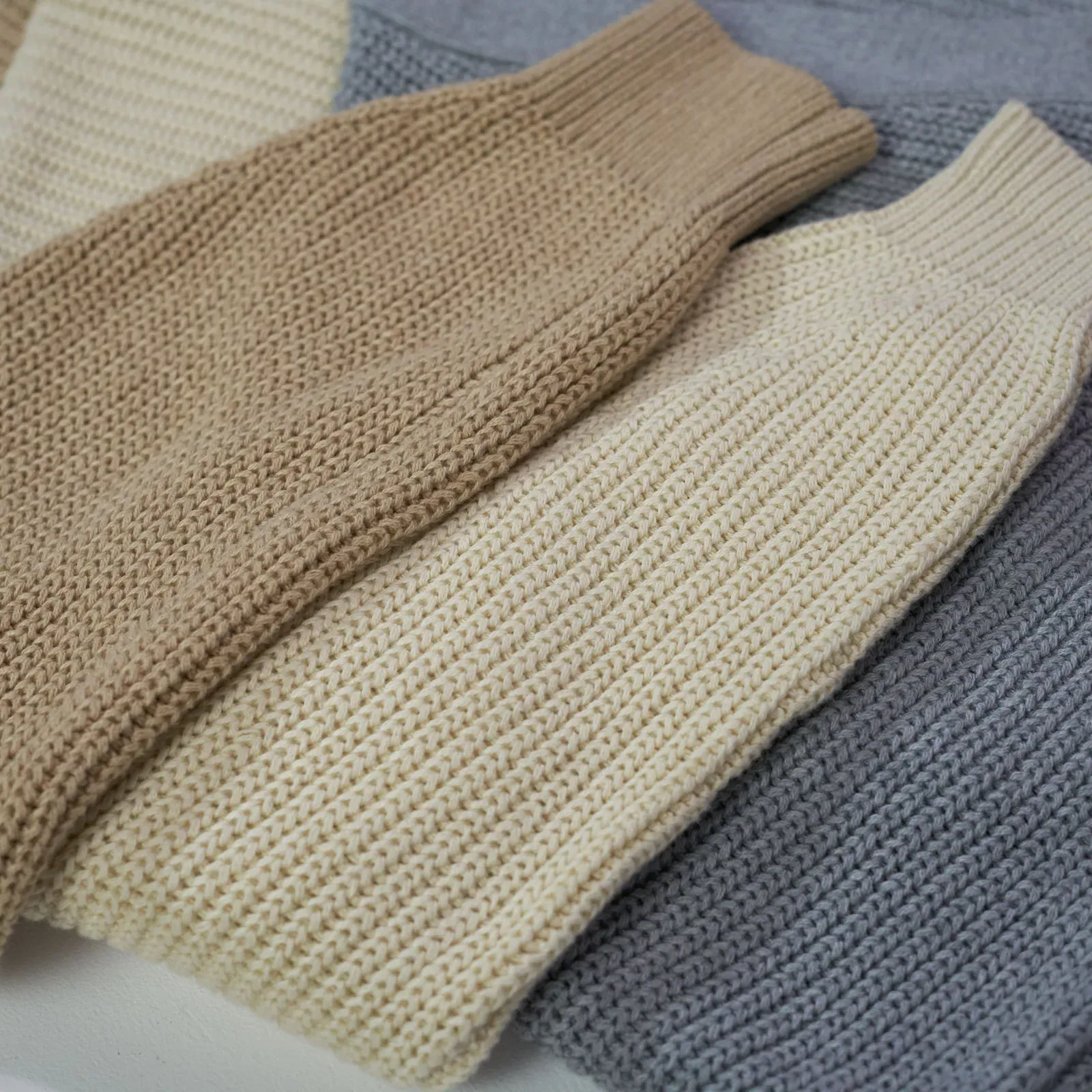 Knit sweaters in camel, cream and grey, close-up