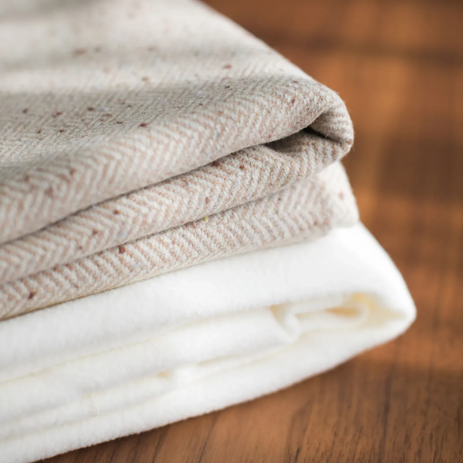 Folded herringbone and cream linen on a wooden table