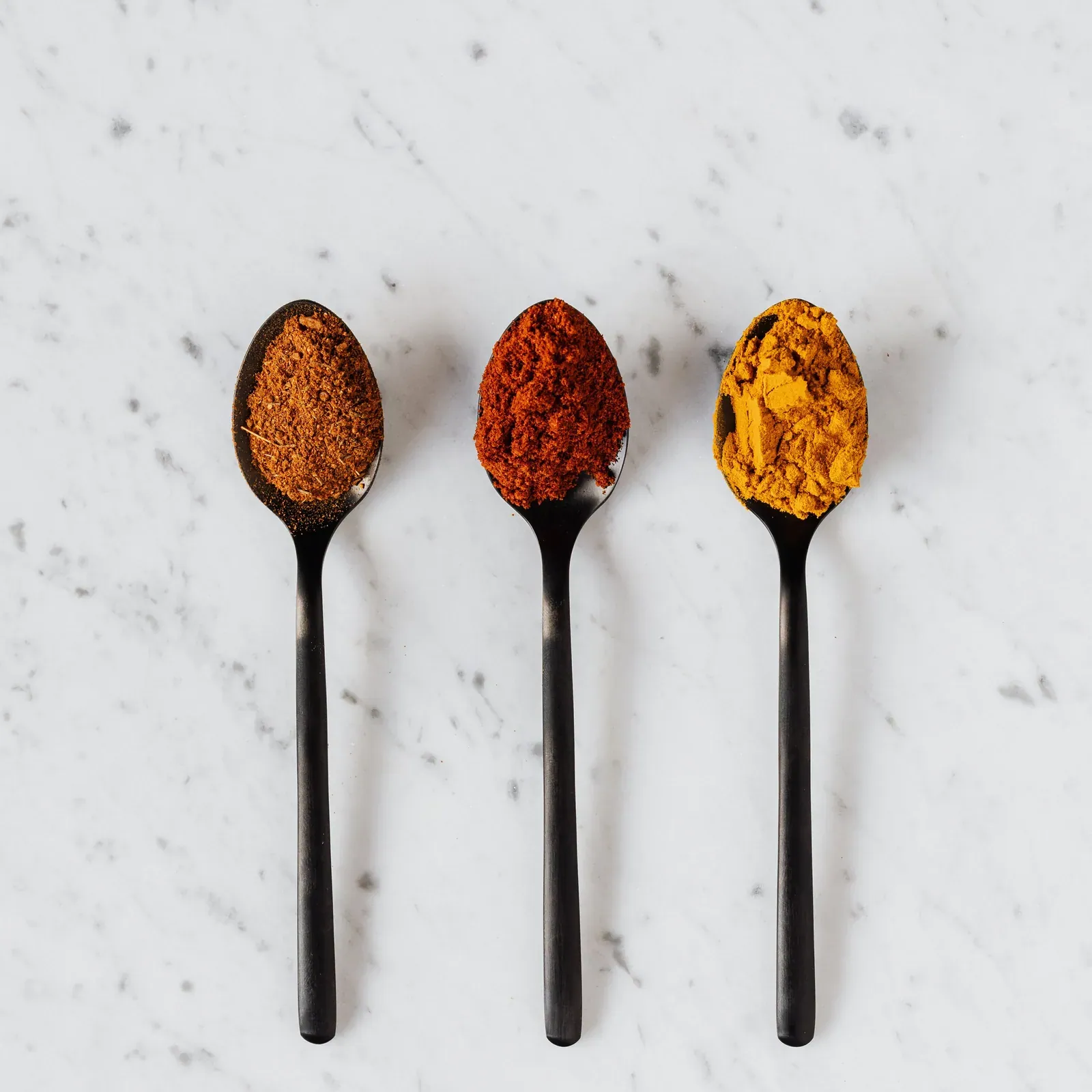 Spoons of ground spices on marble