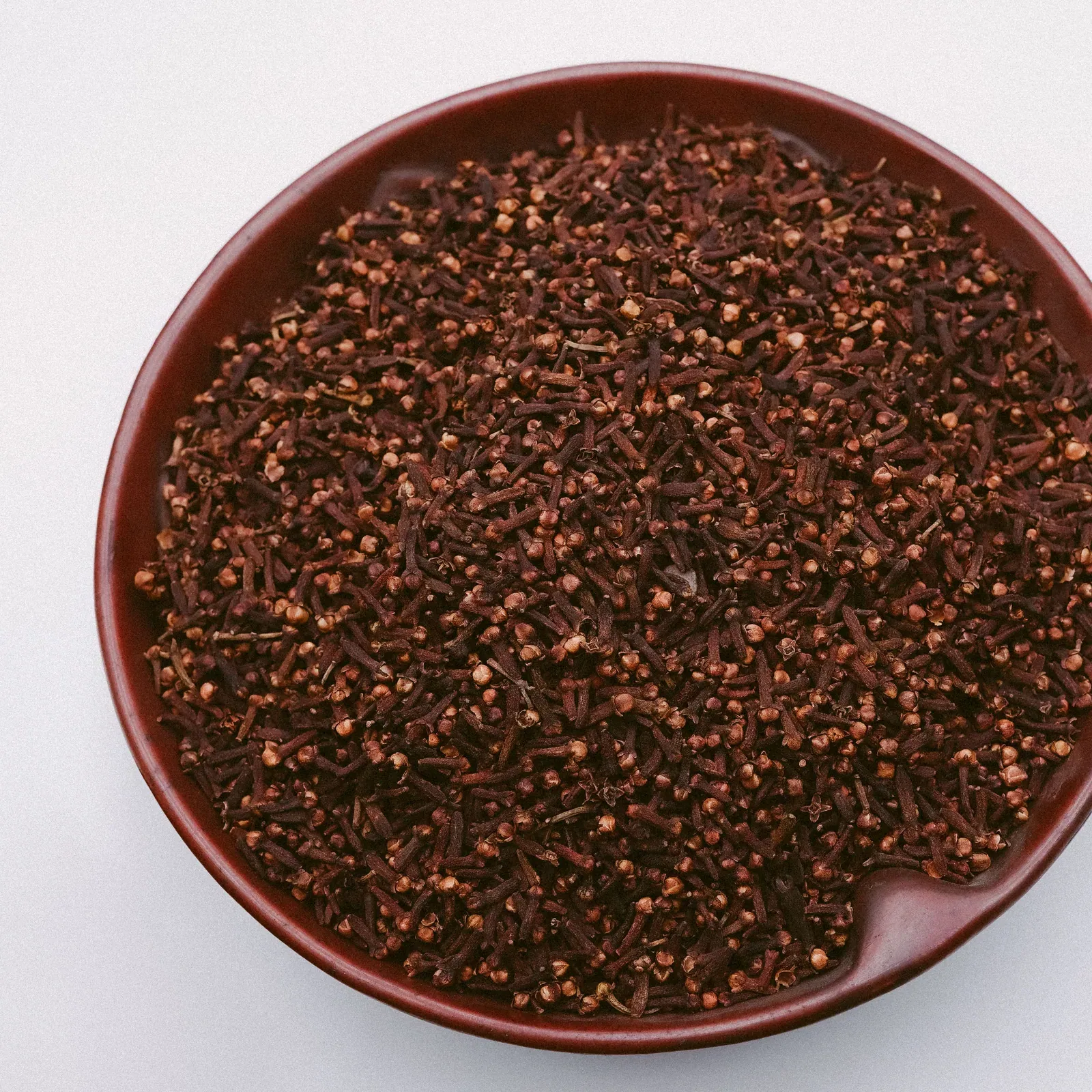 Whole cloves in a brown ceramic bowl