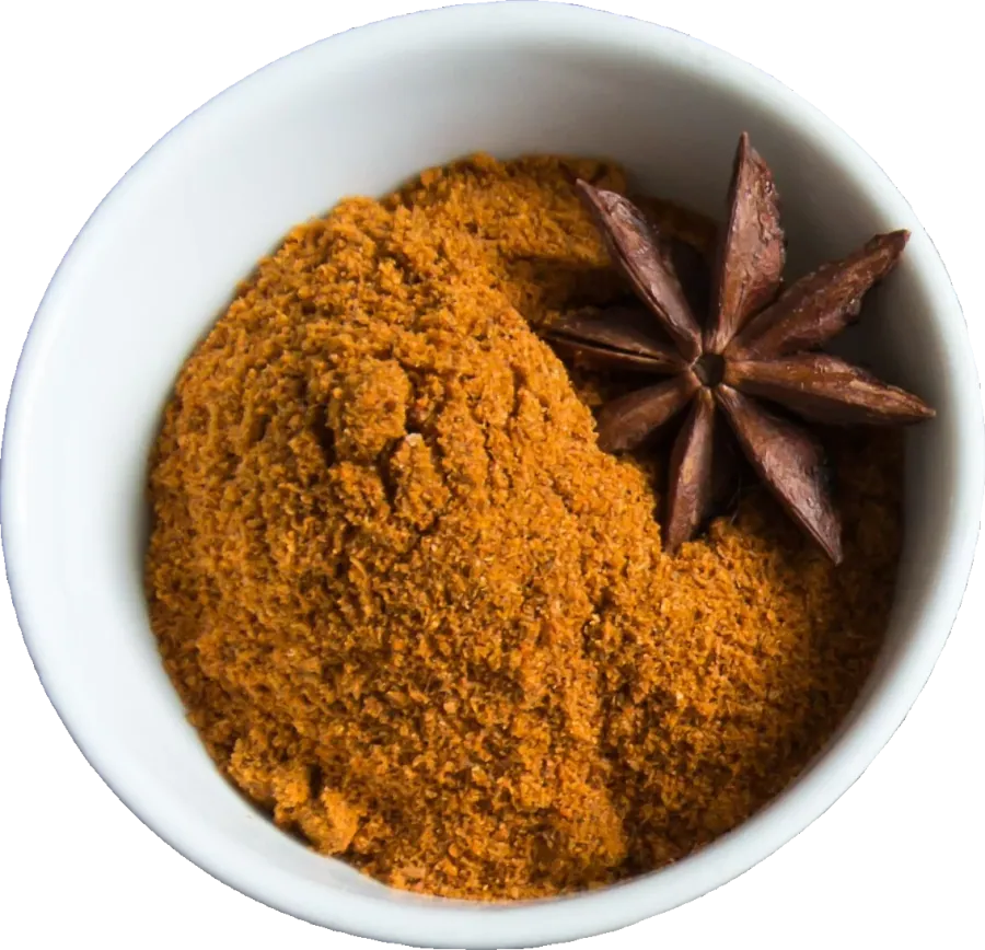 White bowl of ground yellow spice with a star anise