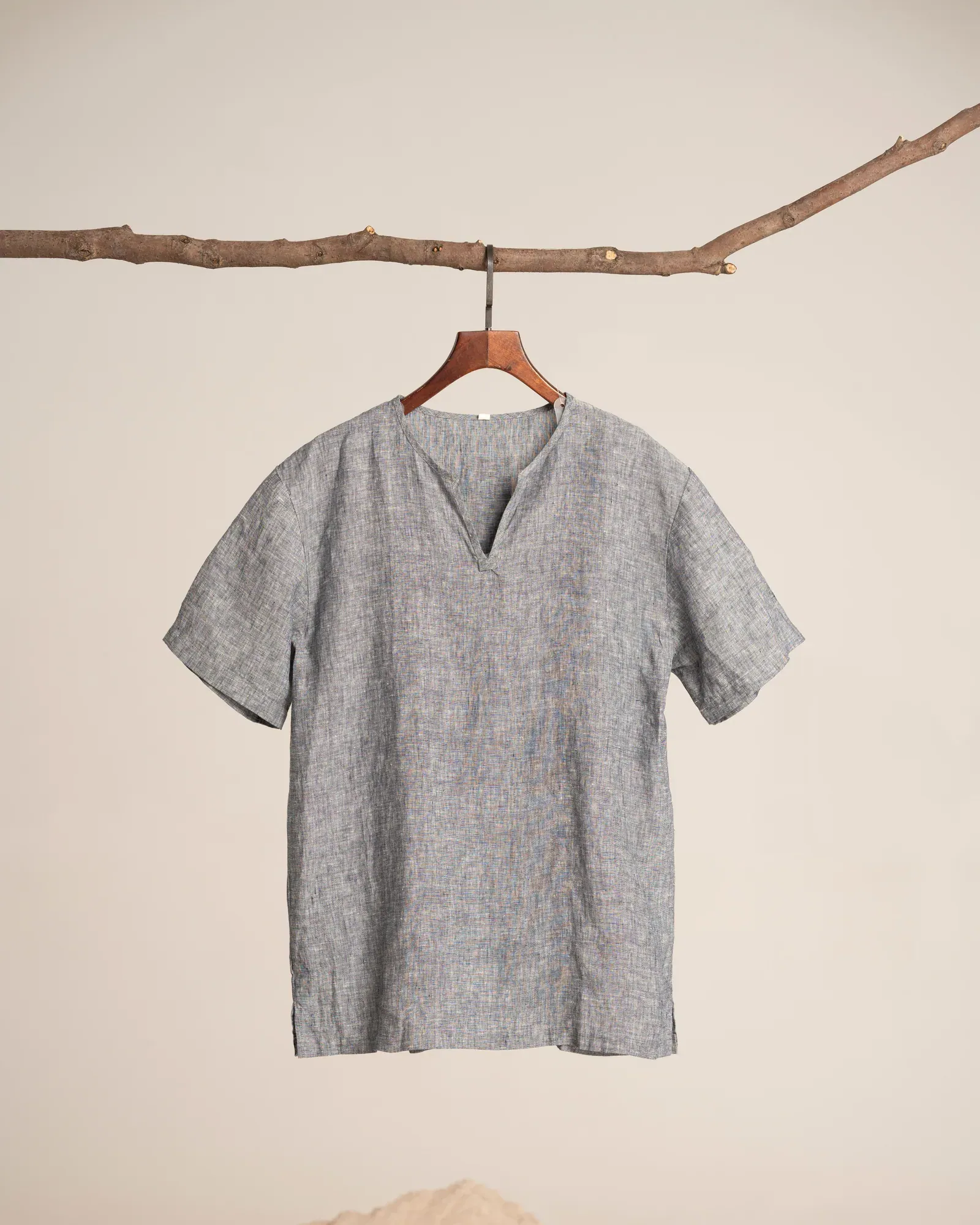 Grey linen T-shirt on a wooden hanger hung from a branch