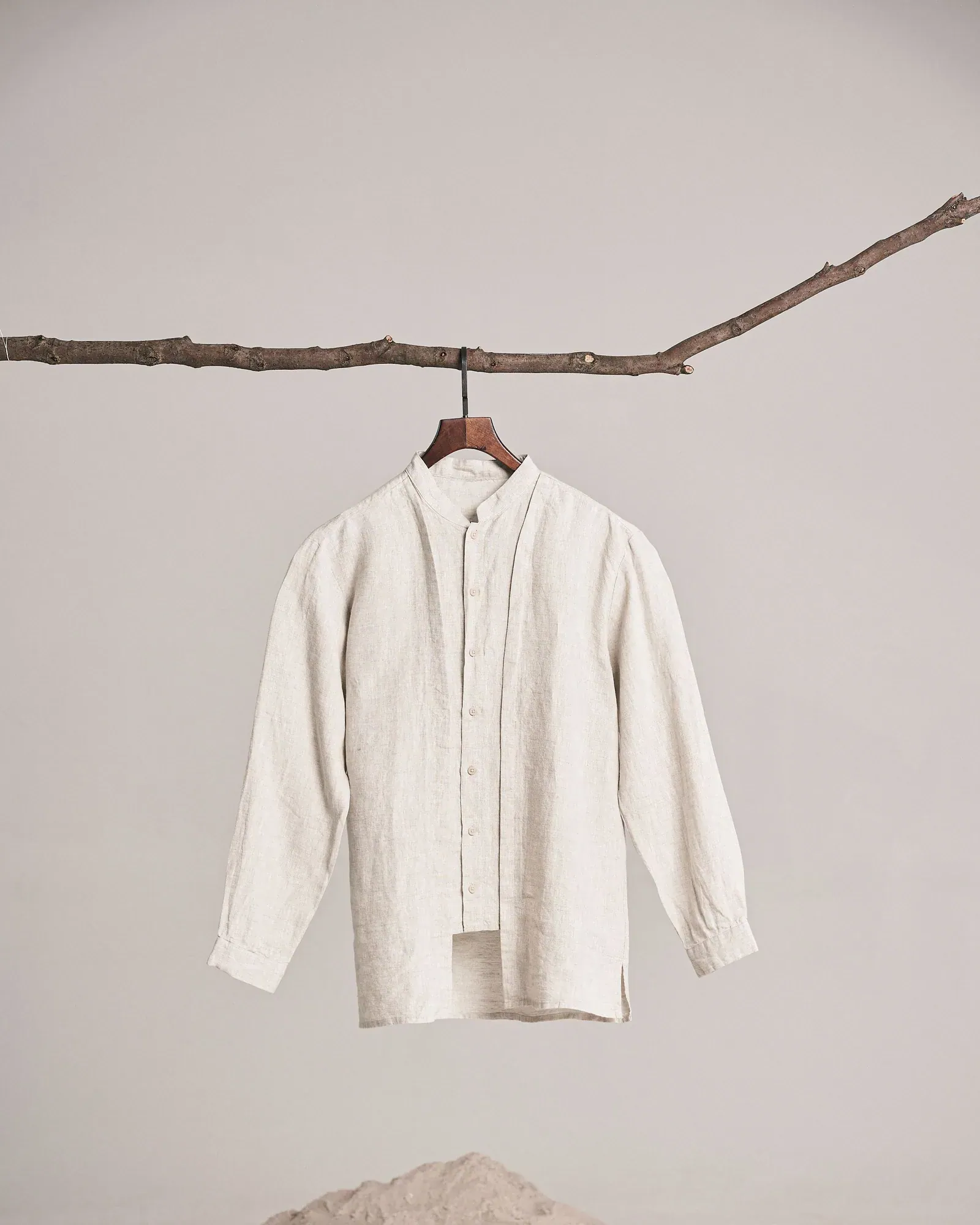 Cream linen shirt on a wooden hanger hung from a branch
