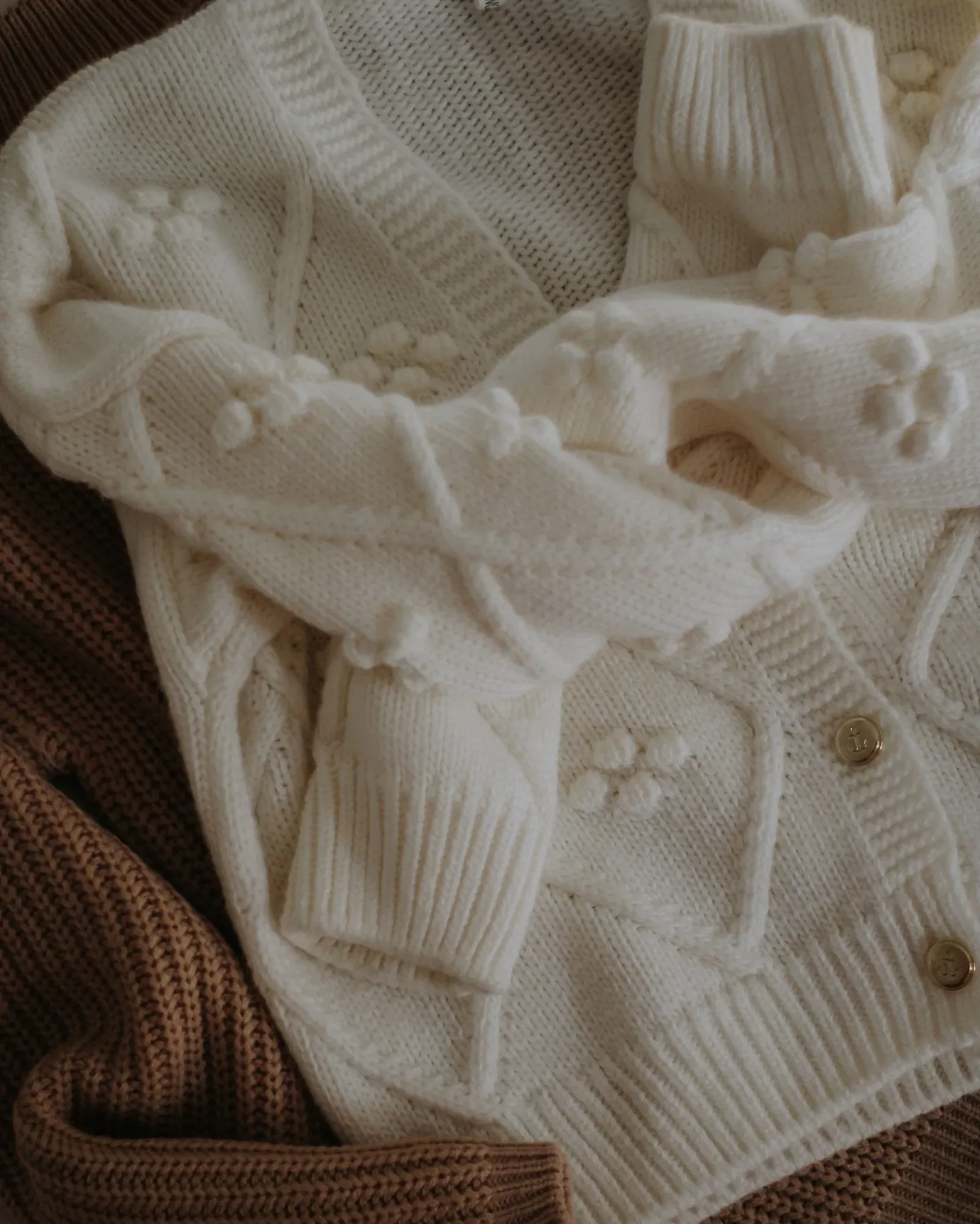 Cream bobble-knit cardigan on a rust knit sweater