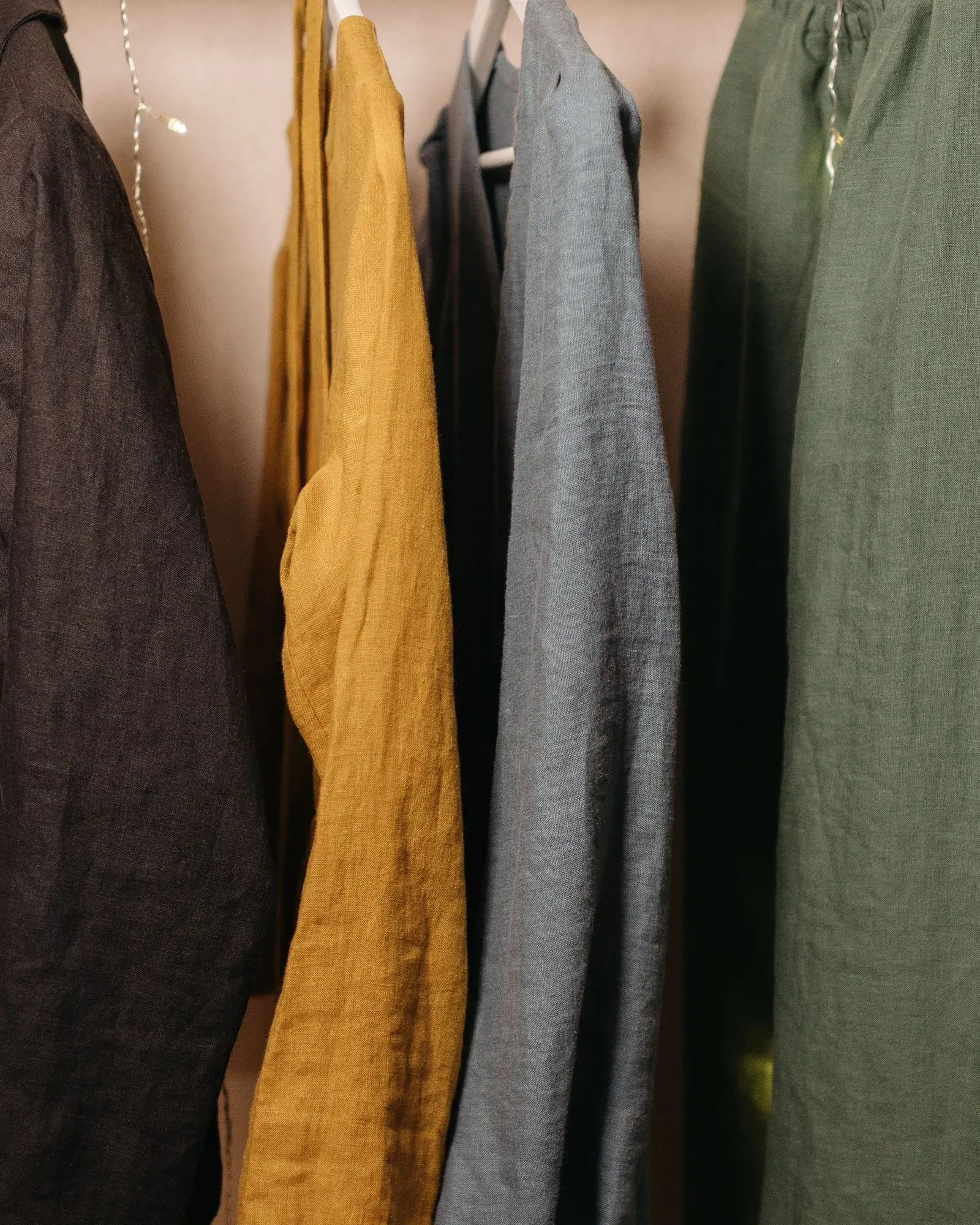 Linen shirts in brown, mustard, grey and olive on hangers