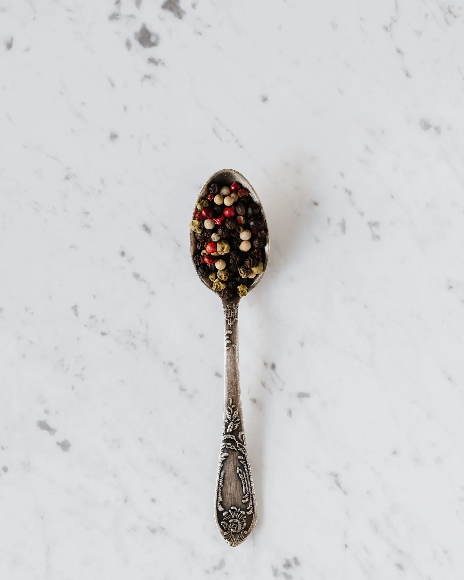 Spoon of mixed peppercorns on marble